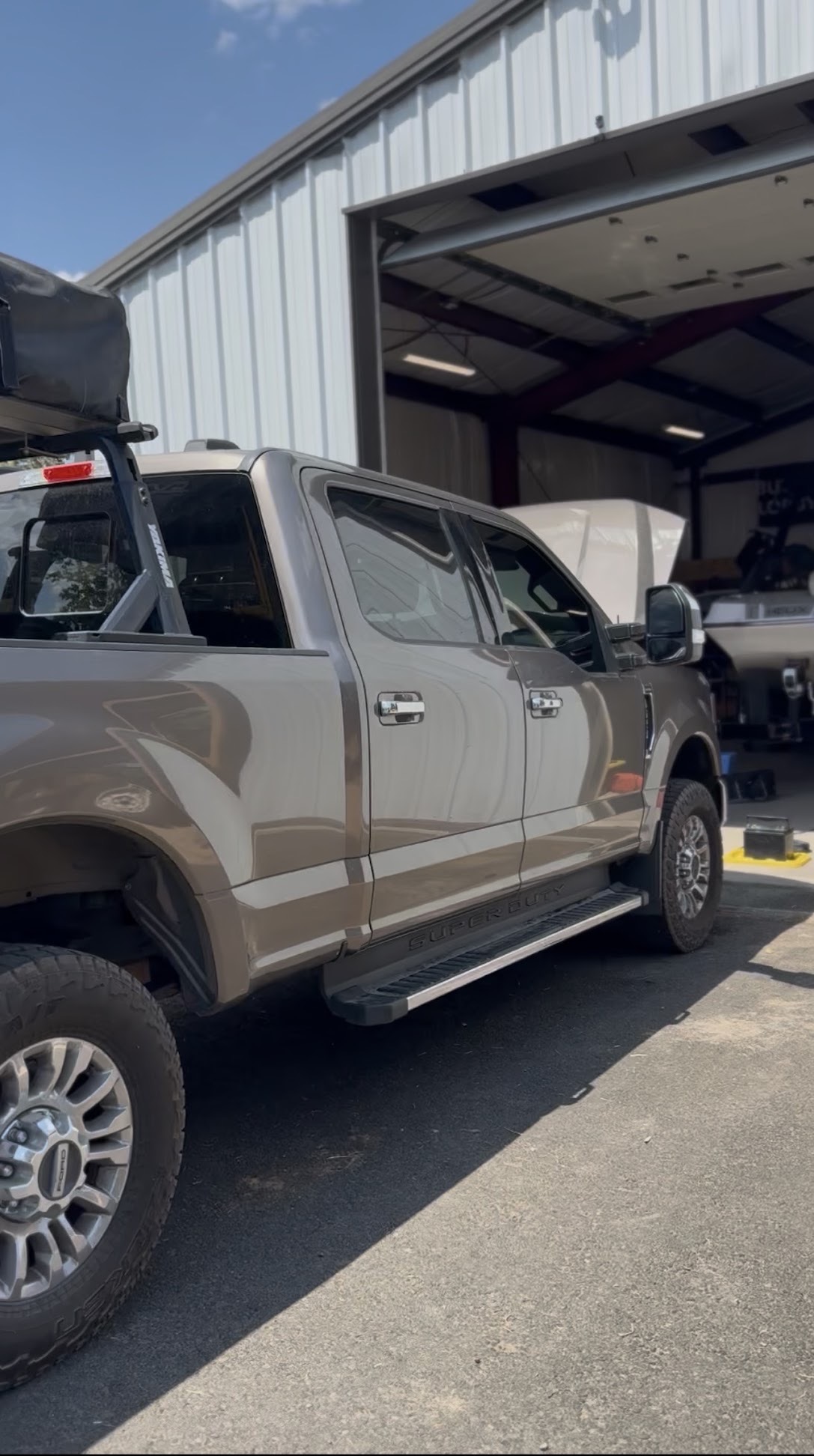 Tan Ford Super Duty crew cab with tinted windows parked at the shop bay